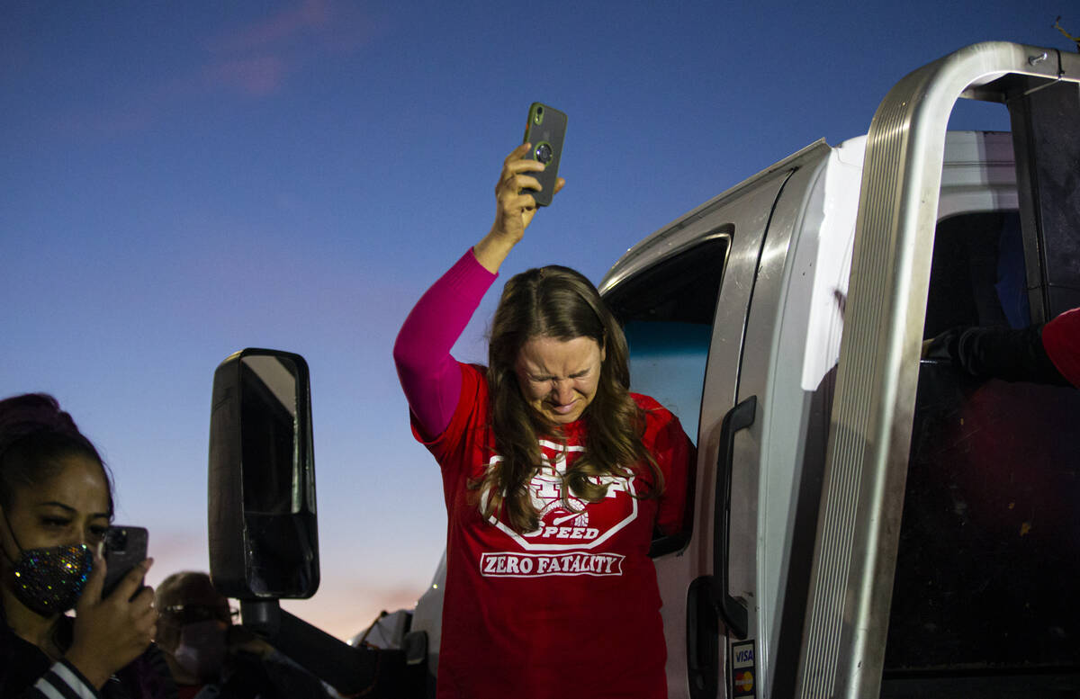 People react during a seven minute moment of silence during a vigil following a vehicle caravan ...