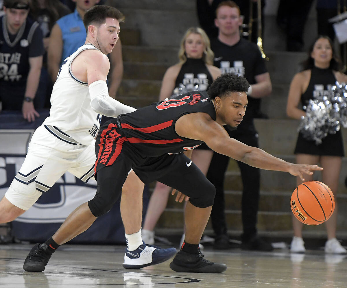 UNLV guard Bryce Hamilton (13) reaches out for the ball as Utah State guard Rylan Jones defends ...