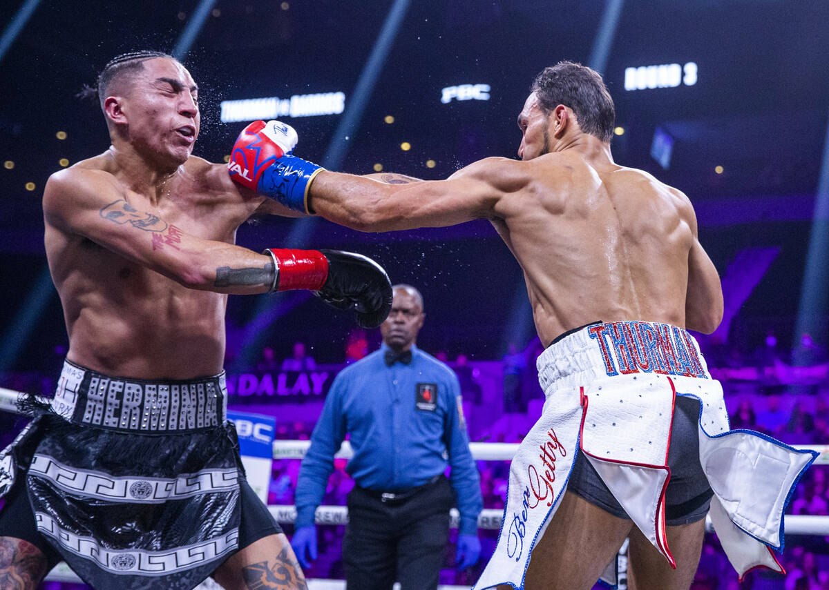 Mario Barrios, left, takes a punch from Keith Thurman during the third round of their Welterwei ...