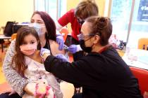 Torrey Cole get a COVID-19 booster shot from Susan Pruitt while her daughter Valentina Morales, ...