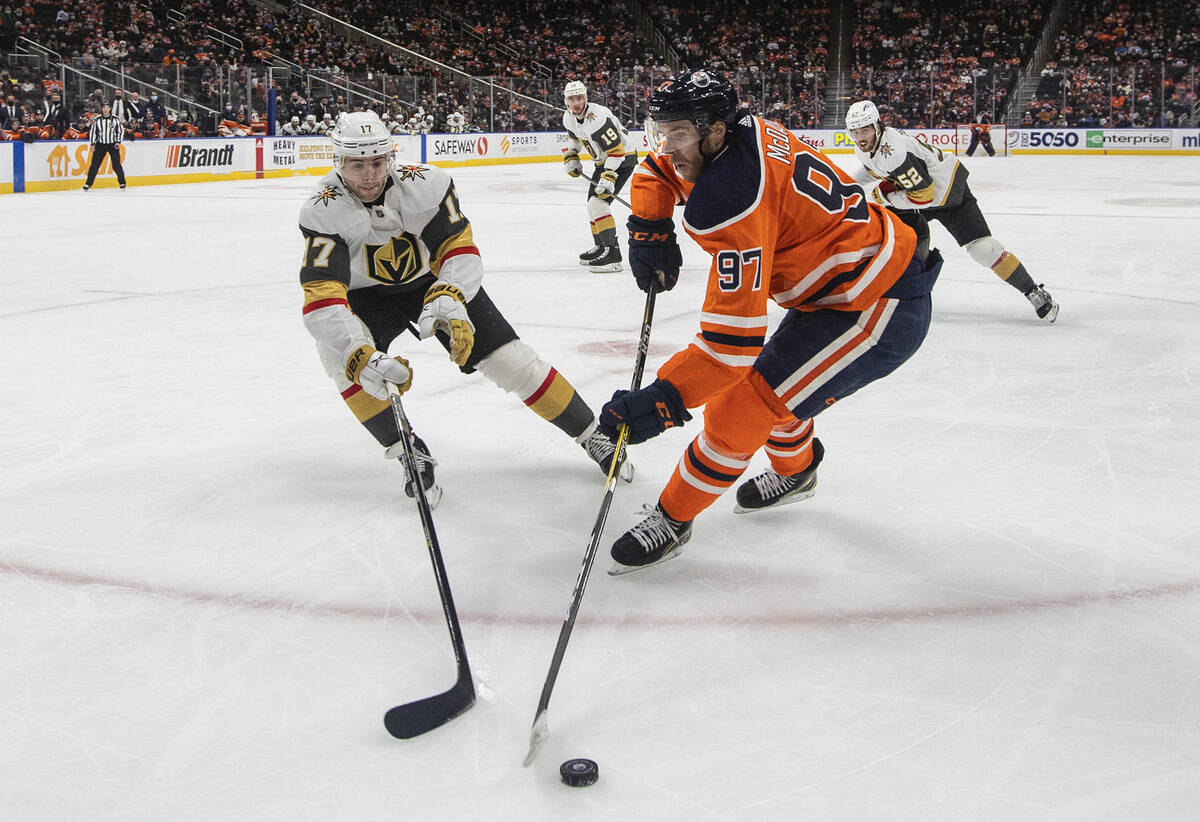 Vegas Golden Knights' Ben Hutton (17) and Edmonton Oilers' Connor McDavid (97) battle for the p ...