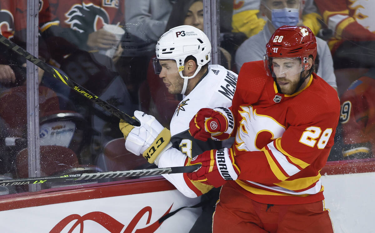 Vegas Golden Knights' Brayden McNabb, left, is checked by Calgary Flames' Elias Lindholm during ...