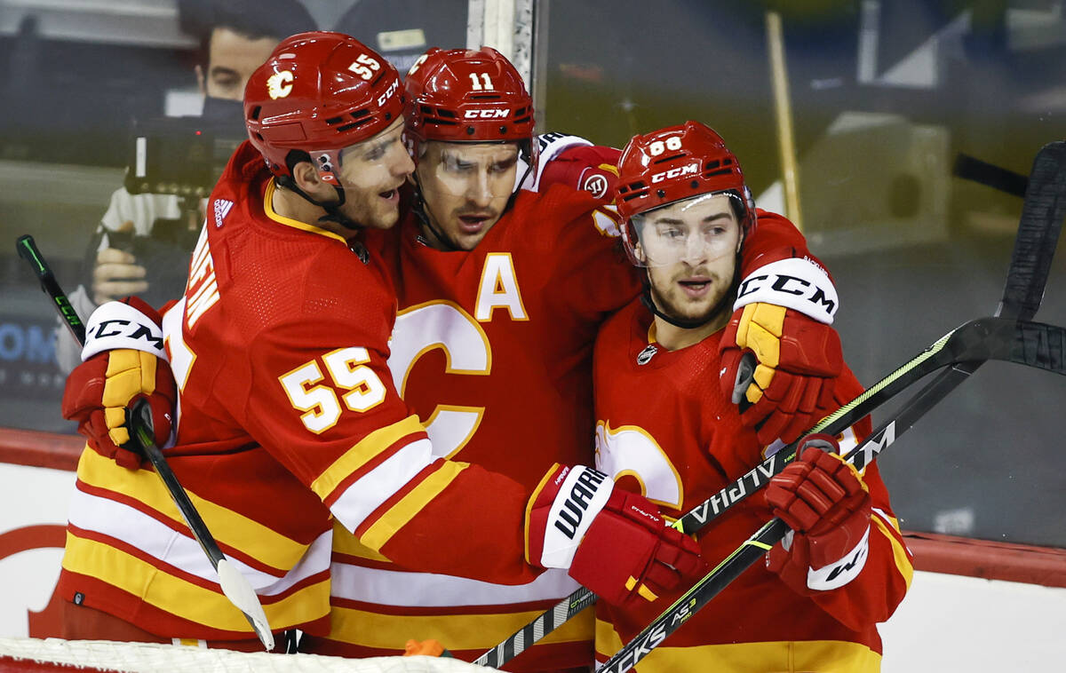 Calgary Flames' Andrew Mangiapane, right, celebrates his goal with teammates Noah Hanifin, left ...
