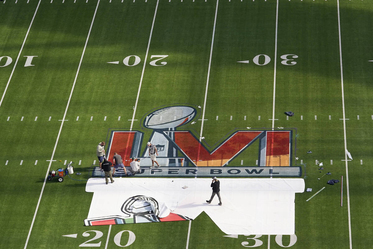 Workers paint a logo on the field at SoFi Stadium as members of the media watch days before the ...