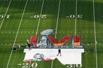 Workers paint a logo on the field at SoFi Stadium as members of the media watch days before the ...