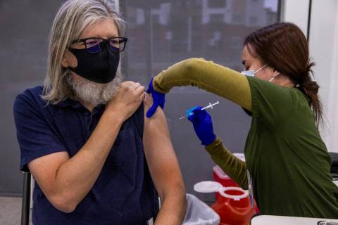 Michael Homa, left, receives a shot from Mary Aldana to while in the COVID-19 vaccination clin ...