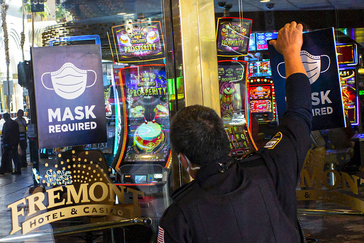 Signs requiring masks are removed by a security officer at the Fremont hotel-casino following t ...