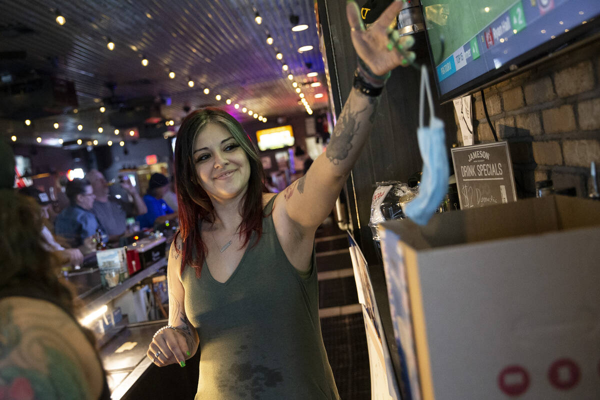 Cruz Justice, bar manager at Gold Mine Tavern, throws away a customer’s mask on Thursday ...