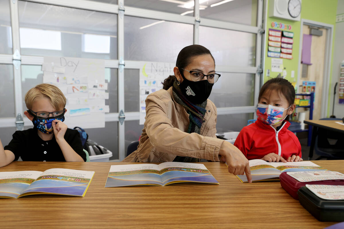 Student teacher Maria Romero works with first graders Kaj Ullom, left, and Lily Lor at Harris E ...