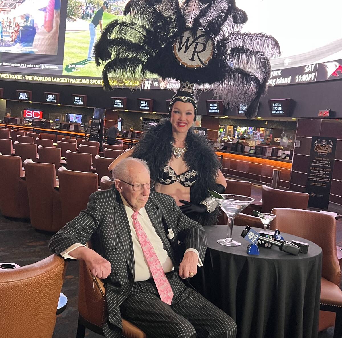 Oscar Goodman mulls his pre-Super Bowl bet at Westgate SuperBook, alongside Showgirl Kristina, ...