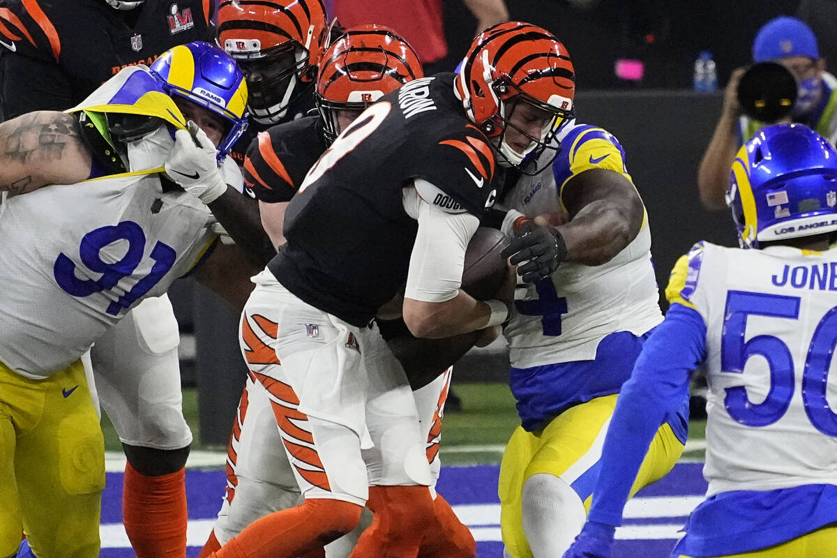 Cincinnati Bengals quarterback Joe Burrow (9) is wrapped up for a sack by Los Angeles Rams duri ...