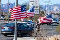 Juanesha Bivens walks along West Sahara Avenue as American flags flutter in the wind on Tuesday ...