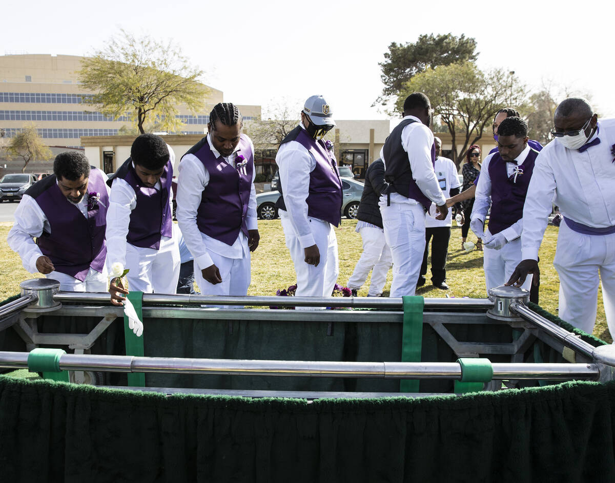 Pallbearers throw their gloves and flowers on the coffin, containing Tanaga Miller, one of 9 pe ...