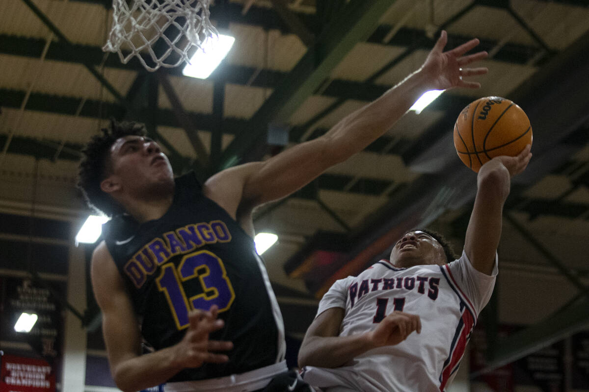 Liberty’s Dedan Thomas (11) shoots against Durango’s Colton Knoll (13) during a high school ...