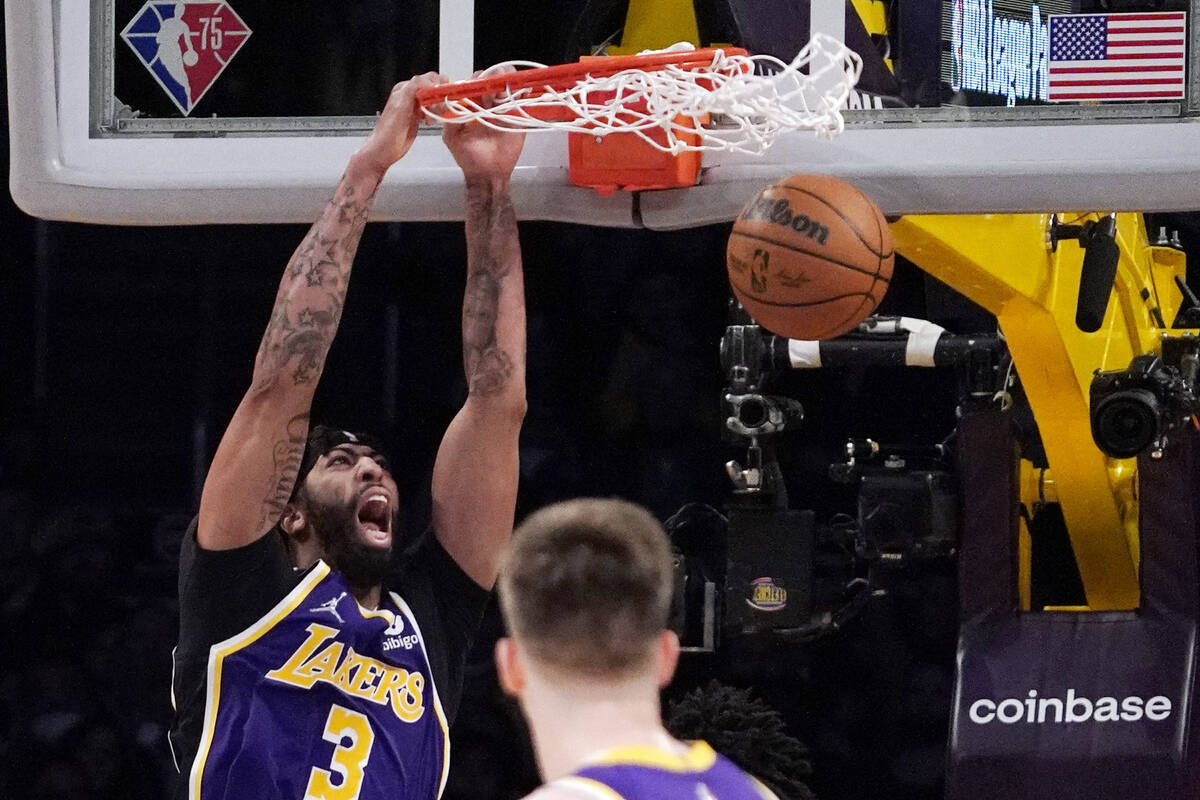 Los Angeles Lakers forward Anthony Davis, left, dunks as guard Austin Reaves watches during the ...