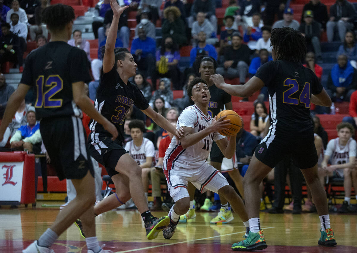 Liberty’s Dedan Thomas (11) drives around Durango’s Sterling Knox (32) and Taj Degourville ...