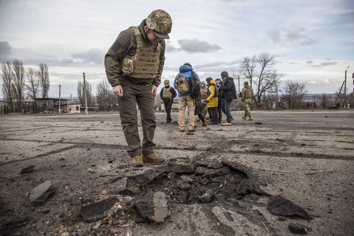 A Ukrainian soldier looks at a hole from a shell fired by pro-Russian separatists in the villag ...