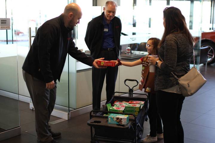 Kevin Hayes, left, and Keith Walton buy Girl Scout cookies from Abbey Forbes, accompanied by he ...