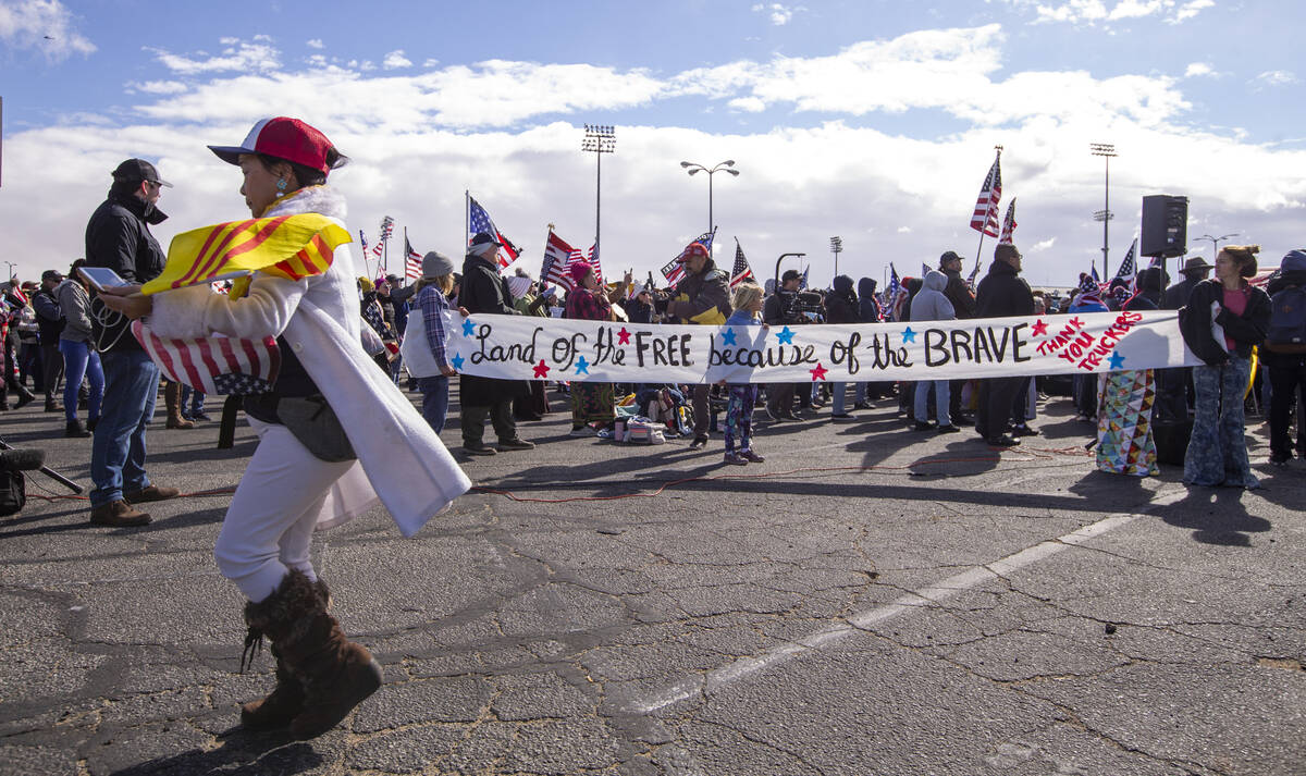 Attendees hold a long sign during a departure event for The People’s Convoy at Adelanto Stadi ...