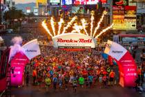 Runners leave the starting line beneath flames during the Las Vegas Rock-N-Roll Marathon along ...