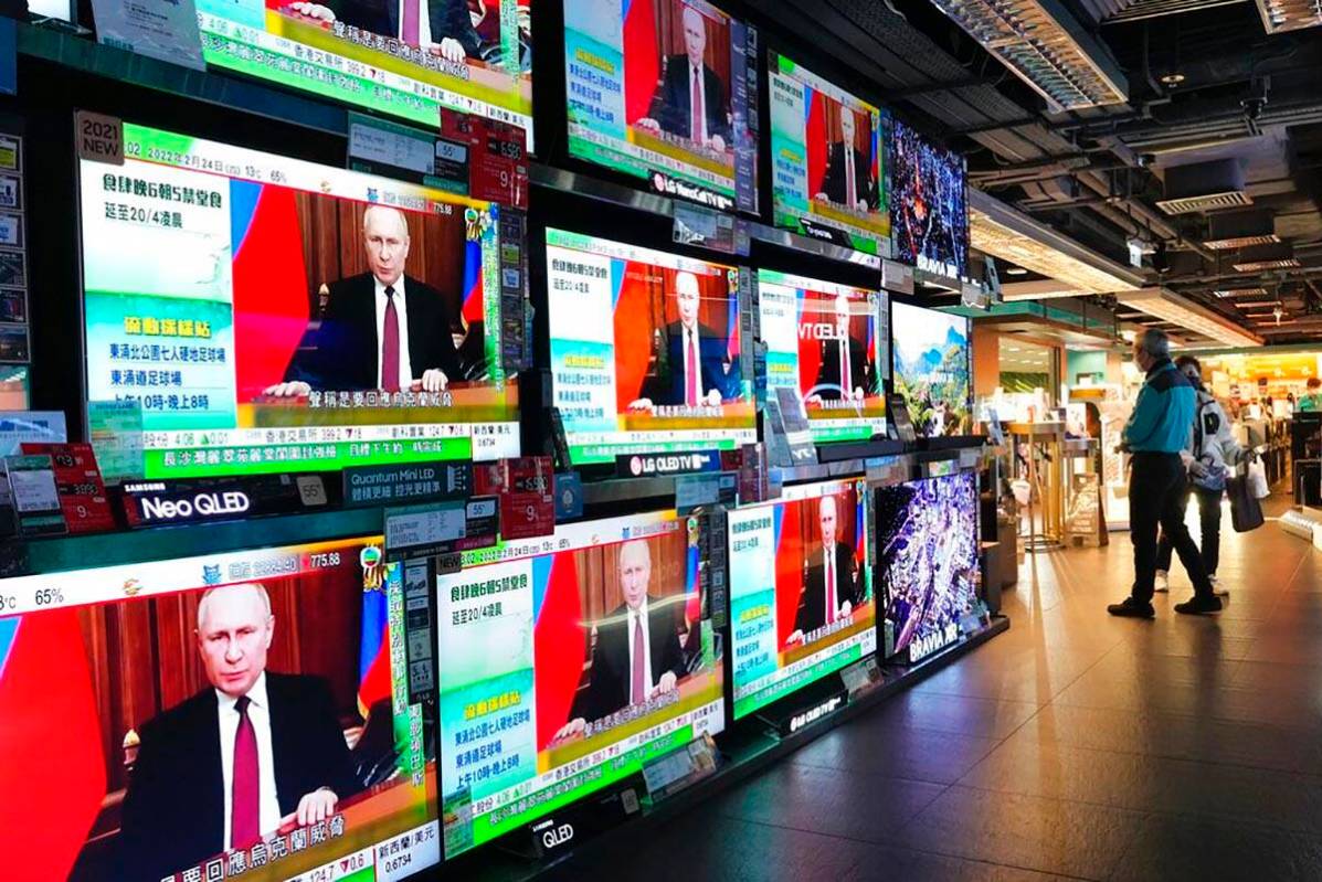 People stand by TV screens broadcasting the news of Russian troops that have launched their att ...