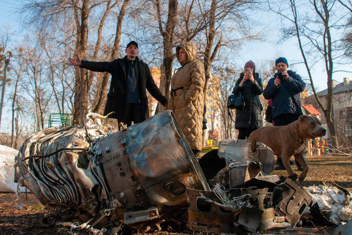 People stand next to fragments of military equipment on the street in the aftermath of an appar ...