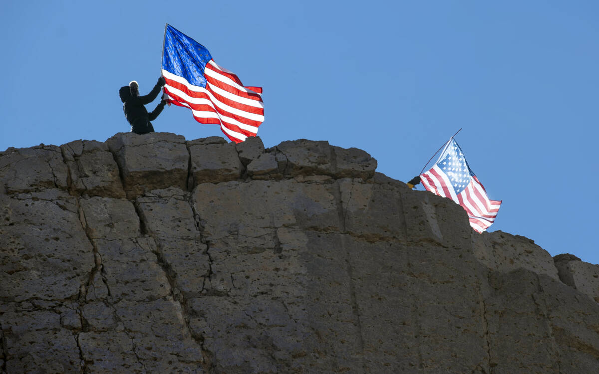 Several supporters fly American flags from atop of a ridge above the I-40 as The People’ ...