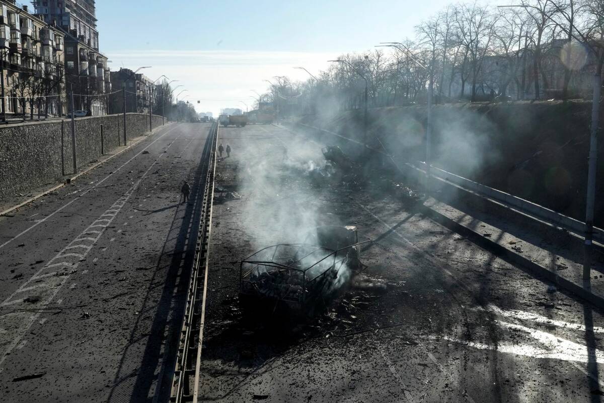 Ukrainian soldiers walk around debris of burning military trucks in a street in Kyiv, Ukraine, ...