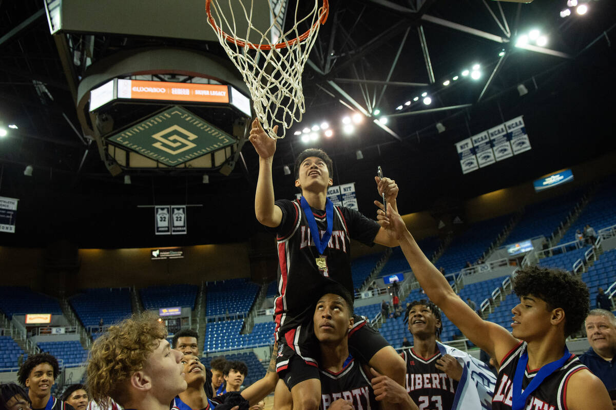 LibertyÕs Noah Madrid cuts down the net at Lawlor Events Center following their NIAA Class ...