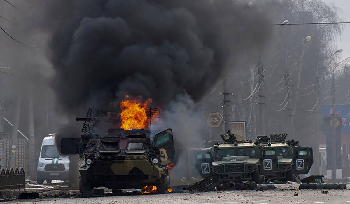 An armored personnel carrier burns and damaged light utility vehicles stand abandoned after fig ...