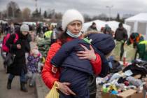 A woman carries her child as she arrives at the Medyka border crossing after fleeing from the U ...