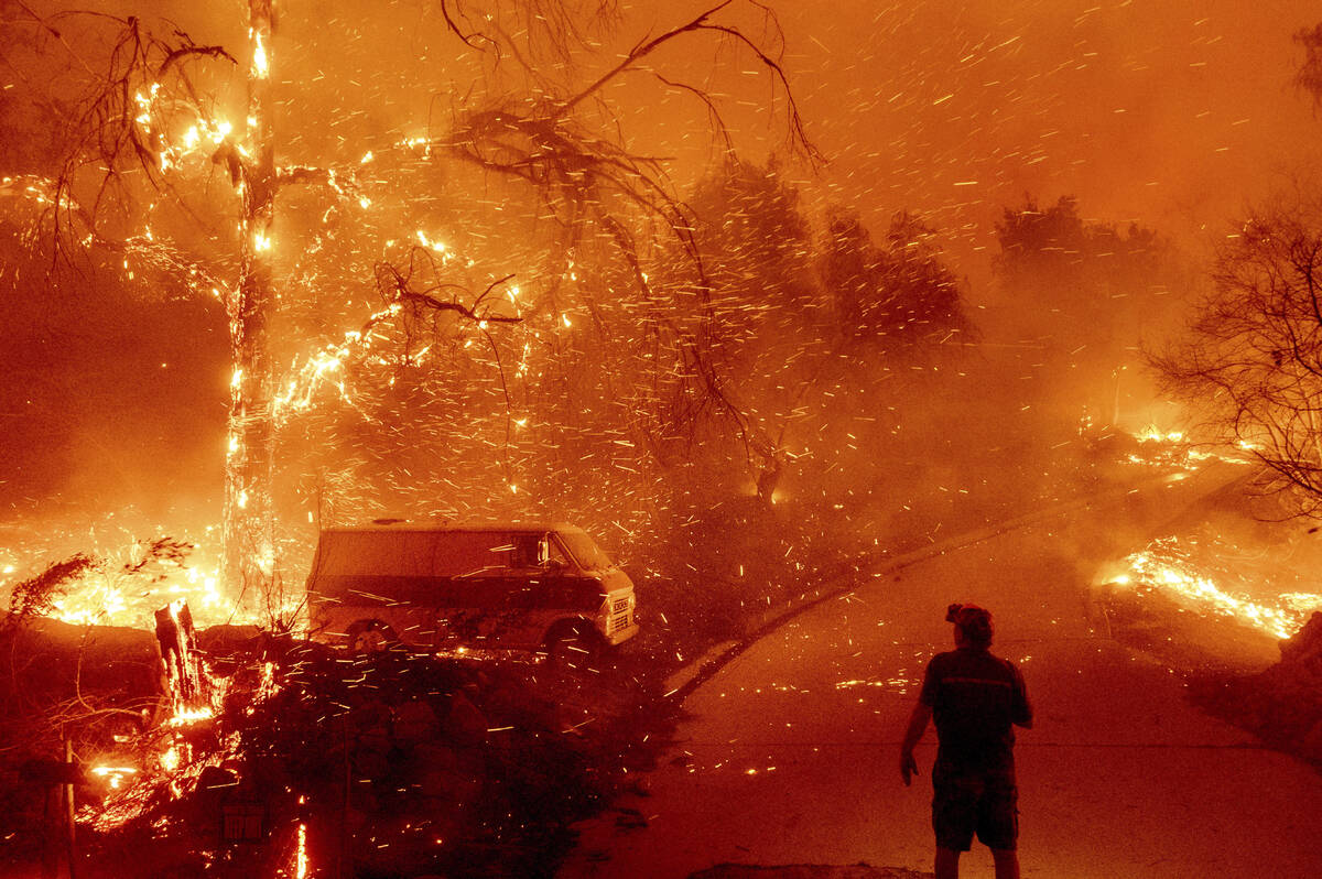 Bruce McDougal watches embers fly over his property as the Bond Fire burns through the Silverad ...