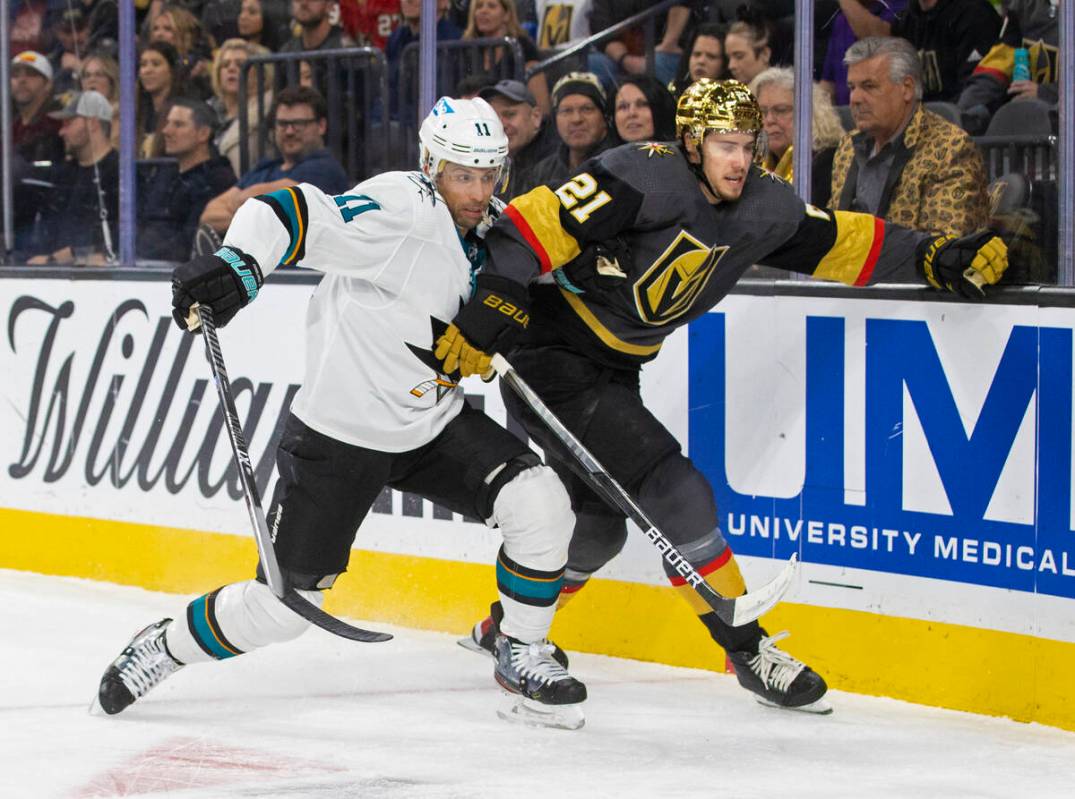 Golden Knights center Brett Howden (21) is checked by San Jose Sharks center Andrew Cogliano (1 ...