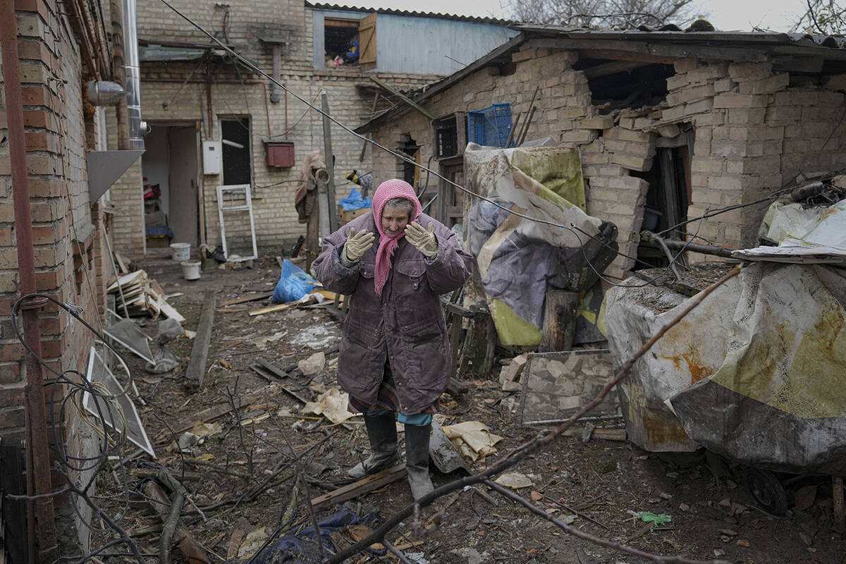 A woman is overwhelmed by emotion in the backyard of a house damaged by a Russian airstrike, ac ...
