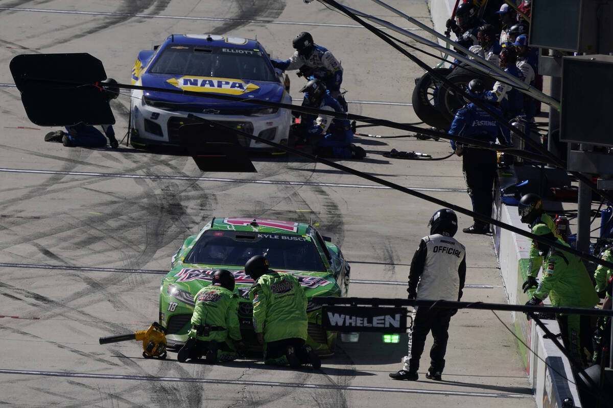 Chase Elliott, top, and Kyle Busch make a pit stop during the NASCAR Cup Series auto race at Au ...