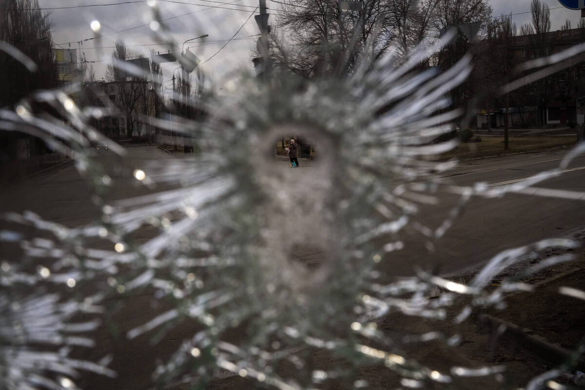 A man is seen through a bullet hole of a machine-gunned bus after an ambush in the city of Kyiv ...