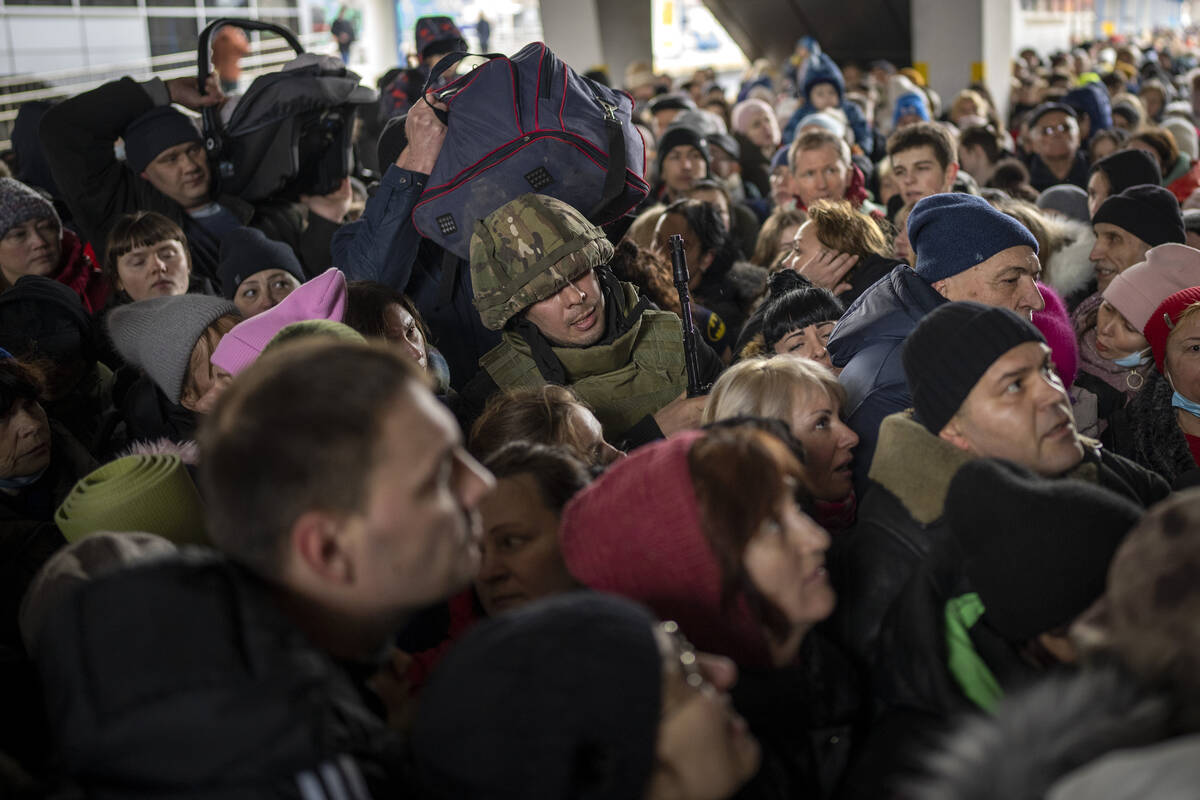 A Ukrainian soldier tries to disperse the crowd as they push to enter a train to Lviv at the Ky ...