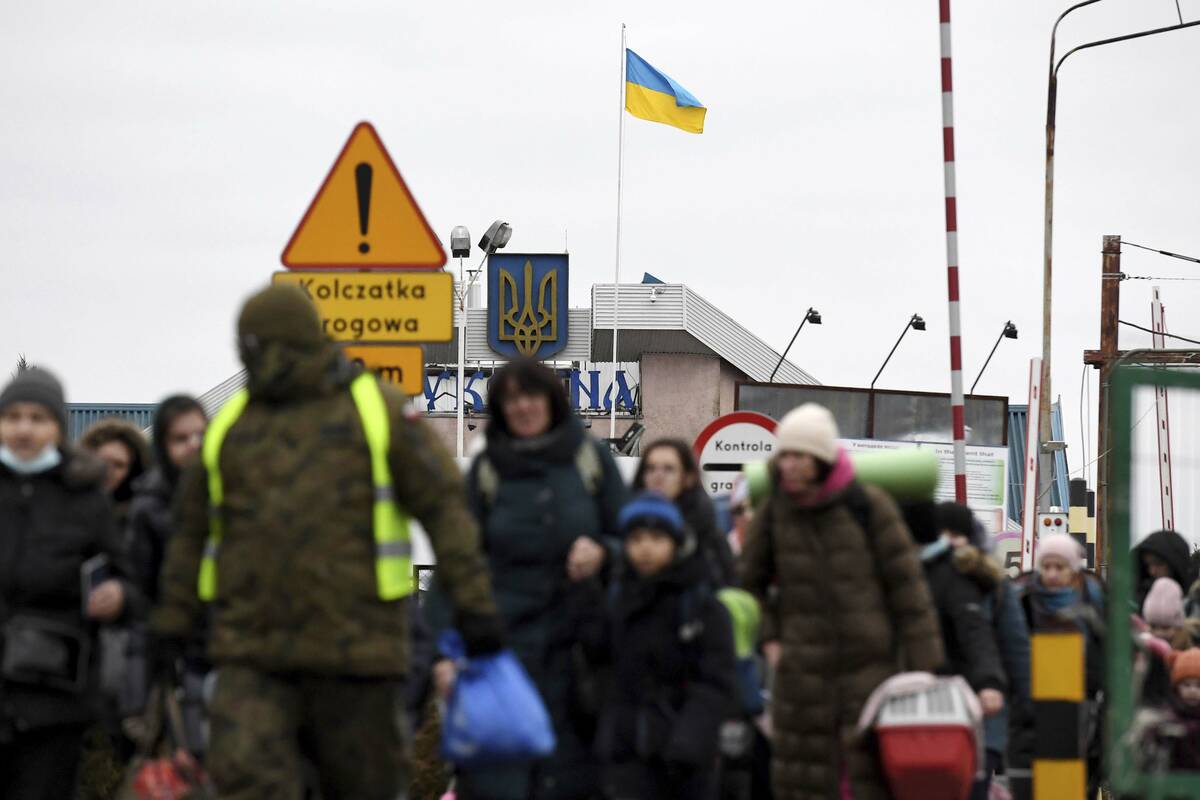 A Ukrainian flag flaps in the wind as people, fleeing Ukraine, cross at the Ukrainian-Polish bo ...