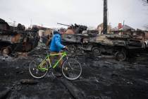 A man walks past the remains of Russian military vehicles in Bucha, close to the capital Kyiv, ...