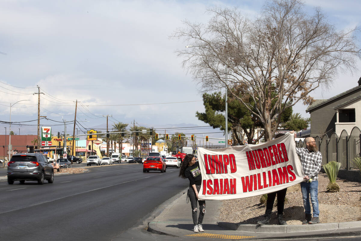 Attendees hold a sign during a press conference held by the family of Isaiah Williams at the ap ...