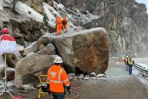 A crew drills holes to place explosives into a large boulder that fell onto U.S. Highway 50 nea ...