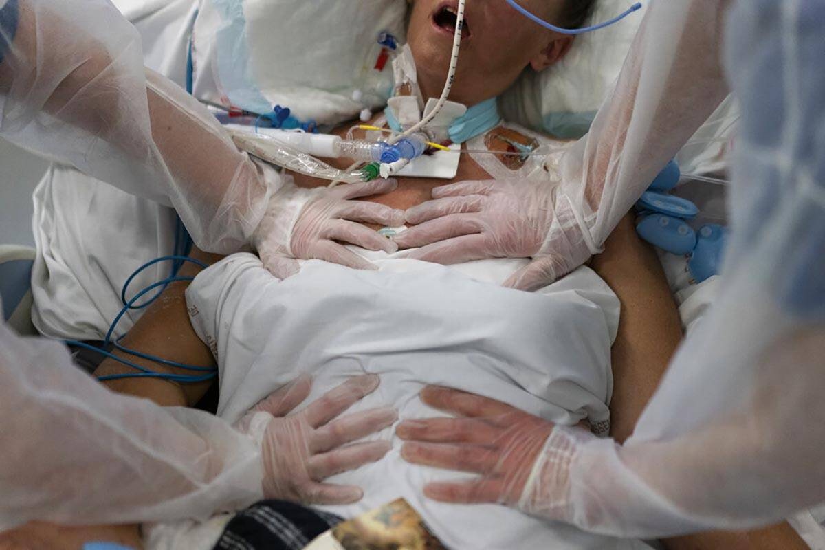 FILE - Nurses perform timed breathing exercises on a COVID-19 patient on a ventilator in the CO ...