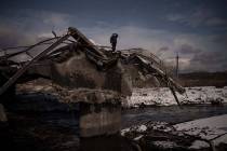A man stands atop a destroyed bridge in Irpin, on the outskirts of Kyiv, Ukraine, Tuesday, Marc ...
