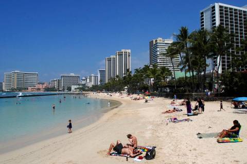 People relax on the beach in Waikiki in Honolulu in 2017. (AP Photo/Caleb Jones)