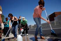 Jen Harney uses a broom and water to clean up sidewalk chalk in front of Las Vegas police headq ...