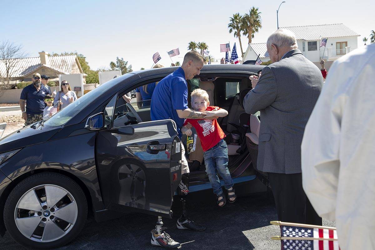 Army Sergeant Adam Poppenhouse lifts his son Senna Poppenhouse, 3, from the car as they arrive ...