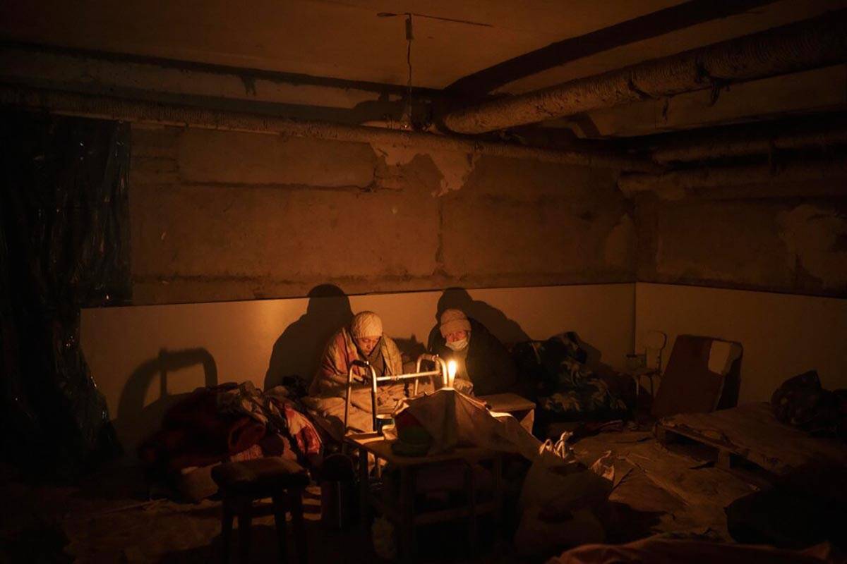 Two elderly woman lit by a candle hide in a basement used as a bomb shelter in Irpin, outskirts ...