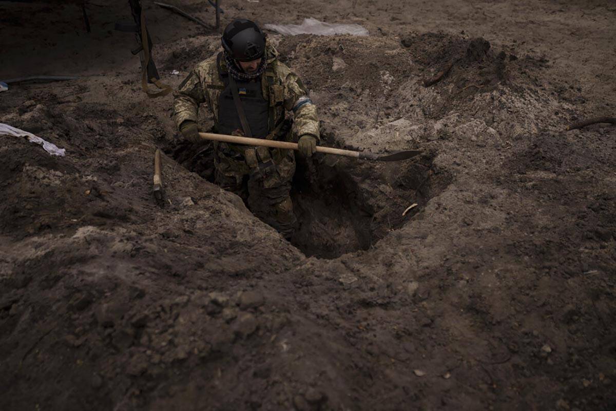 A Ukrainian soldier digs a foxhole in Irpin, outskirts of Kyiv, Ukraine, Sunday, March 13, 2022 ...