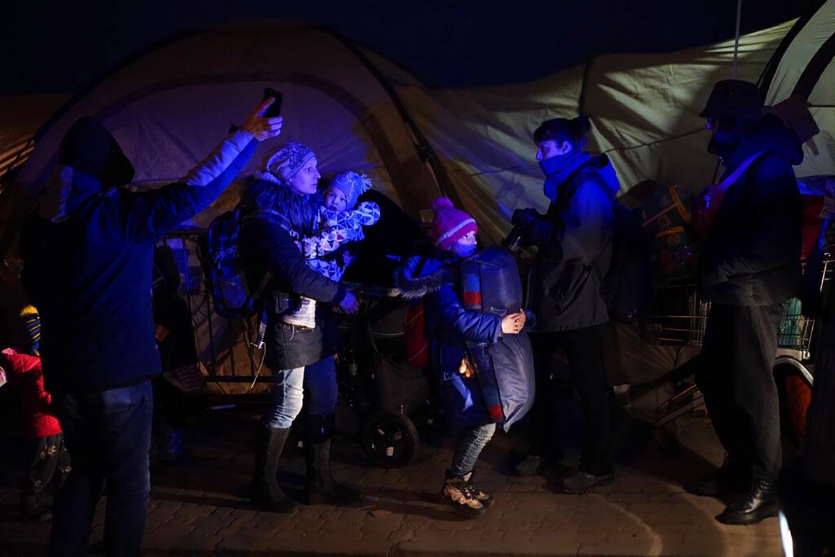 A group of people, who have fled Ukraine, receive directions as they arrive at the border cross ...