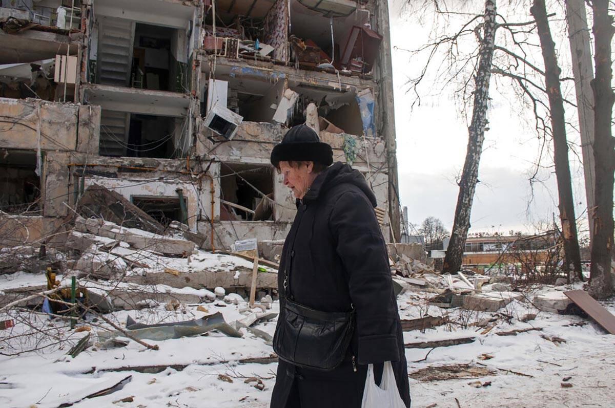 A woman walks past building damaged by shelling, in Kharkiv, Ukraine, Sunday, March 13, 2022. ( ...